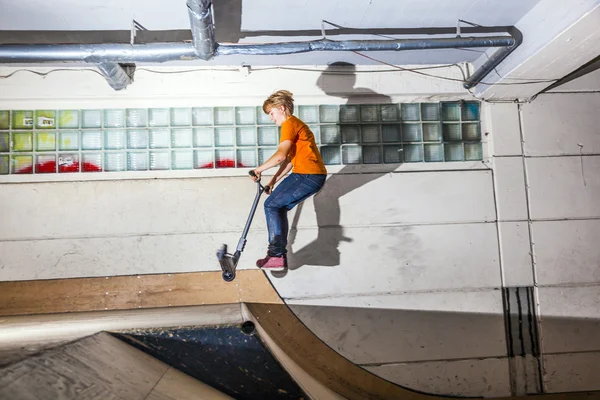 Boy has fun riding his scooter in the skate hall — Stock Photo, Image