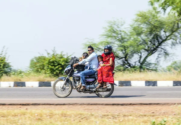 Mother, father and small child riding on scooter through busy hi — Stock Photo, Image