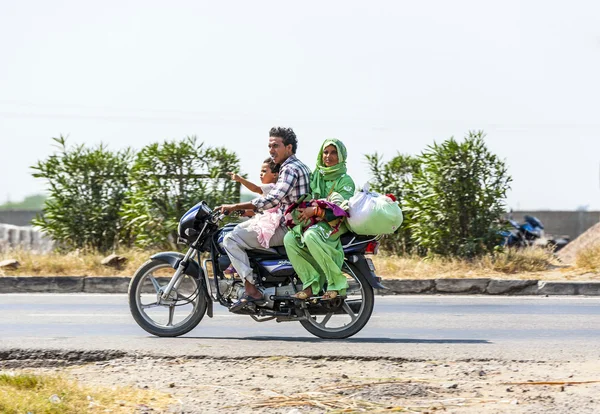 Mother, father and small child riding on scooter through busy hi — Stock Photo, Image