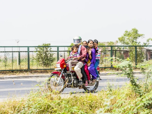 Mother, father and children riding on scooter through highway s — Stockfoto