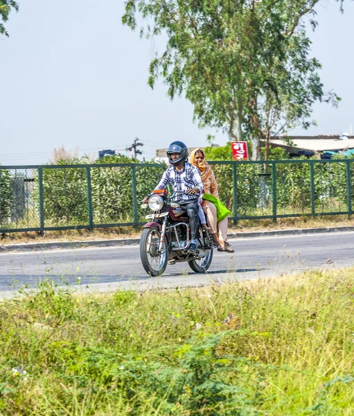 Mujer y hombre montando en scooter a través de la calle carretera ocupada —  Fotos de Stock