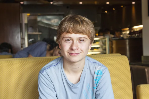 Inteligentny chłopiec siedzi w restauracji fastfood — Zdjęcie stockowe