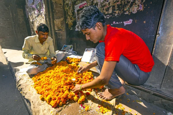 Man threading kleurrijke bloemenslingers — Stockfoto