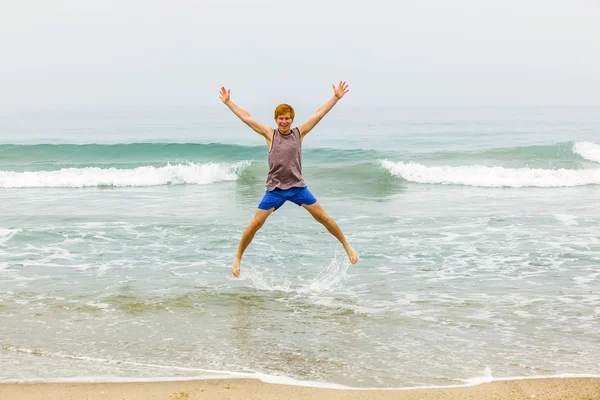Roztomilé dospívající mladík má zábavu na pláži — Stock fotografie
