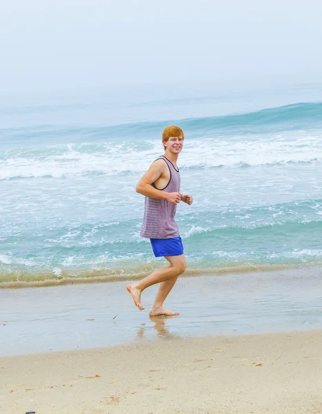 Mignon jeune adolescent garçon jogging à la plage vide le matin — Photo