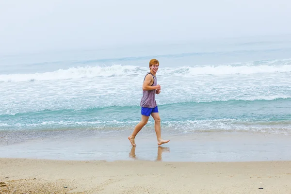 Mignon jeune adolescent garçon jogging à la plage vide le matin — Photo