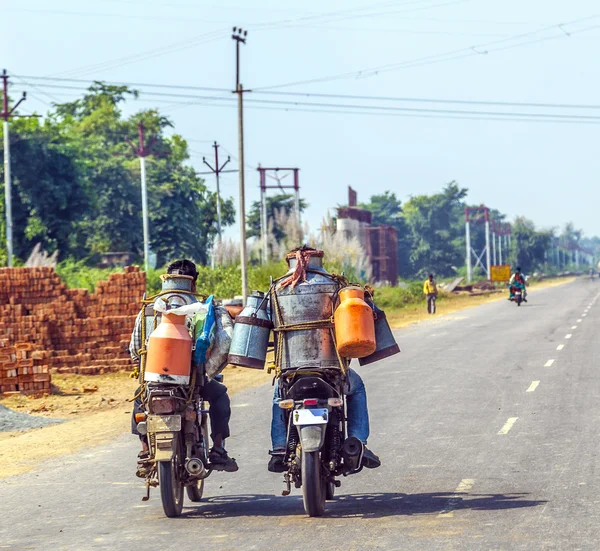 Homens andando de moto com latas de leite — Fotografia de Stock