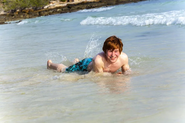 Jongen geniet liggen in de spume van het tropisch strand — Stockfoto