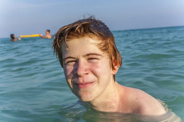 Jongen met rood haar is genieten van het duidelijk warm water op de beauti — Stockfoto