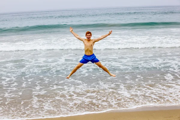 Garçon saute dans les airs à la plage — Photo