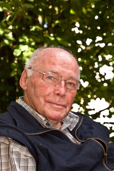 Vieil homme assis sur une chaise dans son jardin et semble très frite — Photo