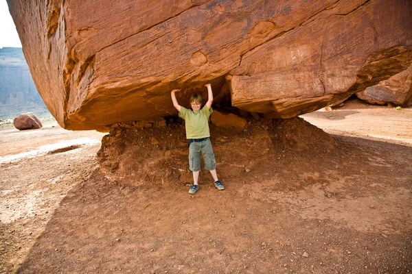 Monument Valley, criança se diverte por simulações para transportar um grande roc — Fotografia de Stock