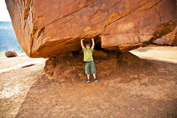 Monument Valley, criança se diverte por simulações para transportar um grande roc — Fotografia de Stock