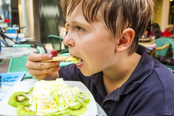 Criança está comendo gelado em uma mesa ao ar livre — Fotografia de Stock