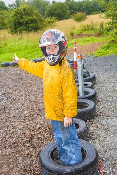 Rapaz feliz com capacete na trilha de kart — Fotografia de Stock