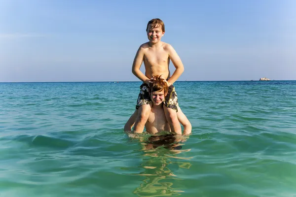 Fratelli stanno godendo la limpida acqua calda nell'oceano e giocare Foto Stock