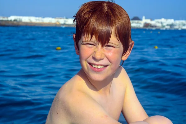 Rapaz bonito em um barco com pele molhada — Fotografia de Stock