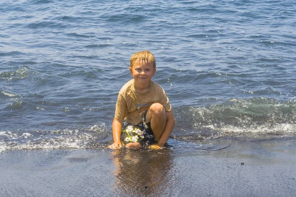 Pojken har kul att spela i vågor — Stockfoto