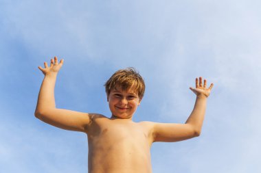 mutlu gülümseyen genç oğlan mavi gökyüzünün altında sahilde poz