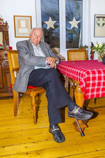 Gamla farfar sitter med sin käpp vid bordet — Stockfoto