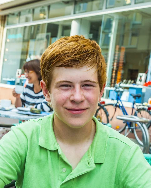 Pojke med rött hår ser glad och vänlig — Stockfoto