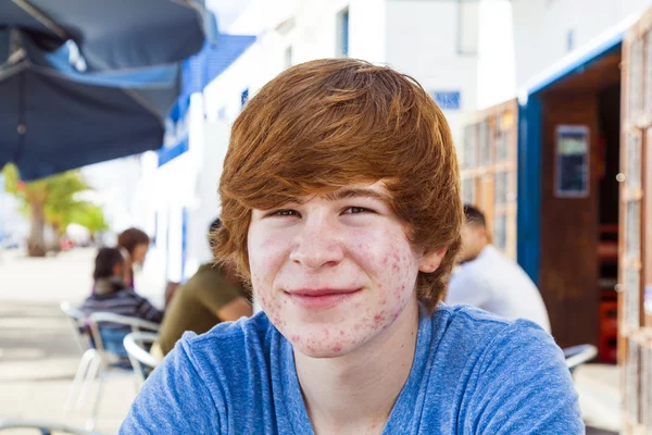 Chico inteligente en la pubertad sentado en una mesa al aire libre en el pueblo — Foto de Stock