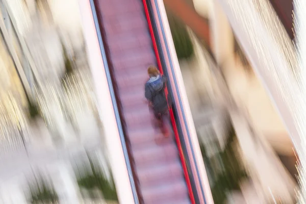 Mujer en una escalera en movimiento en el centro comercial — Foto de Stock