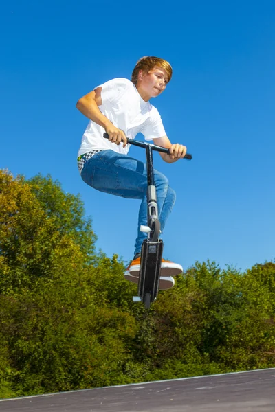 Jongen springen met zijn scooter — Stockfoto