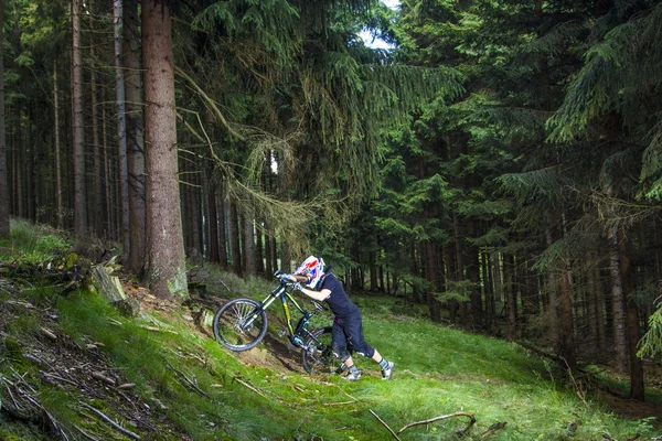 Downhill rowerzysta skacze na ziemi w lesie — Zdjęcie stockowe