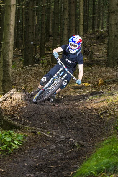 Downhill-Biker springt im Wald über eine Rampe — Stockfoto