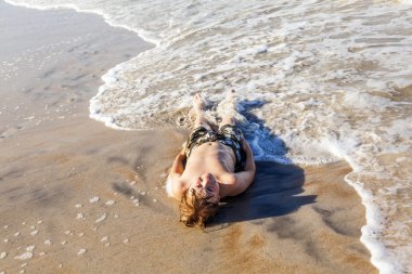 plajda yatan ve güneşin tadını çocuk