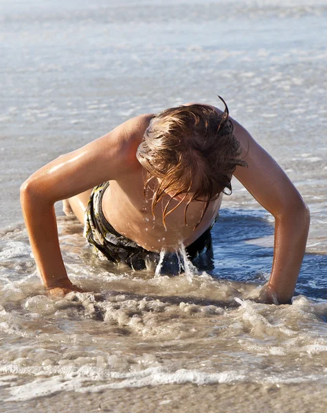 Fiatal fiú pushups, a gyönyörű tengerparton gyakorlása — Stock Fotó