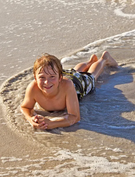 Niño tumbado en la playa y disfrutando del sol —  Fotos de Stock