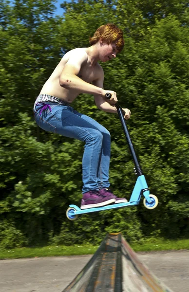 Jeune garçon va dans les airs avec un scooter — Photo