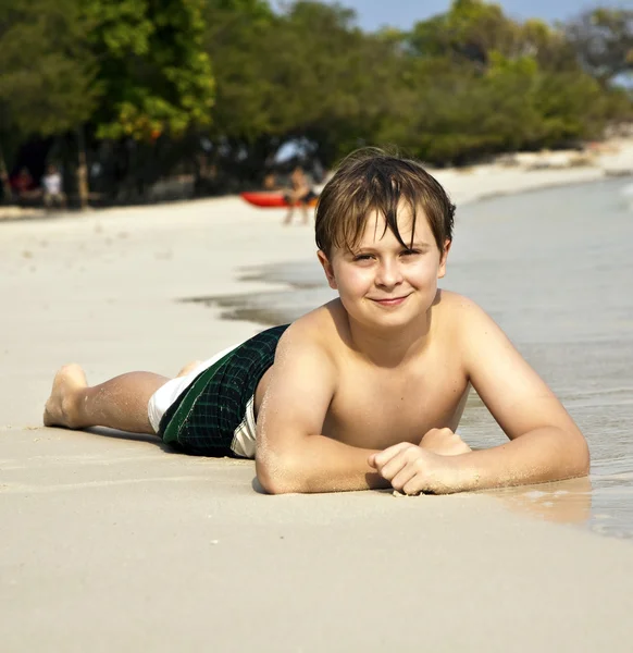 Rapaz feliz deitado na praia — Fotografia de Stock