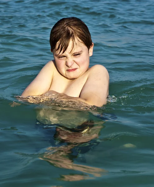 Pojken njuter det klara varma vattnet på den vackra stranden men — Stockfoto