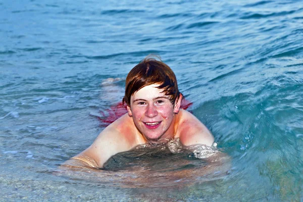 Boy lying at the beach enjoys the surf of the ocean — Stock Photo, Image