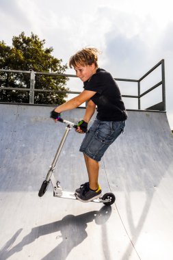 Çocuk halfpipe onun scooter ile atlama sahiptir.