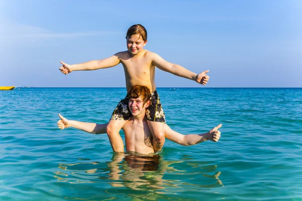 Hermanos están disfrutando del agua caliente clara en el océano y jugar —  Fotos de Stock