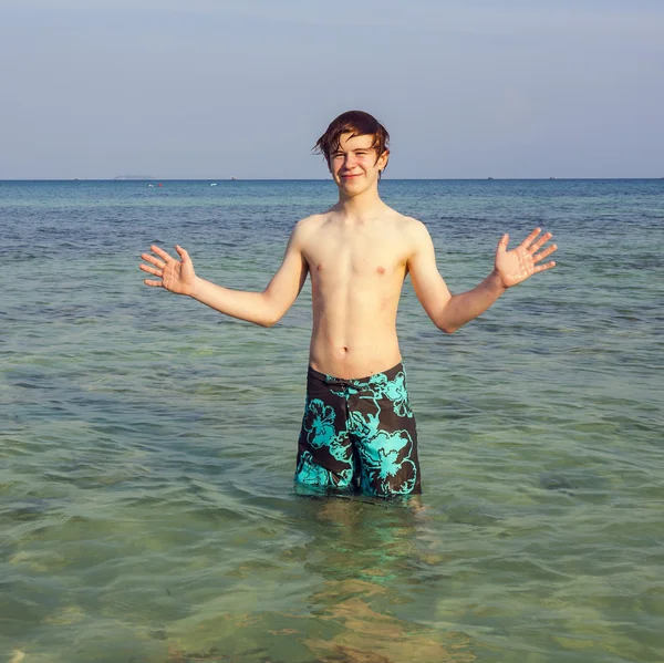 Jovem rapaz está de pé no belo mar claro e goza do — Fotografia de Stock