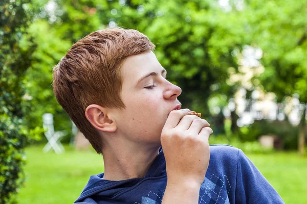 Jongen een brood eten in de tuin — Stockfoto