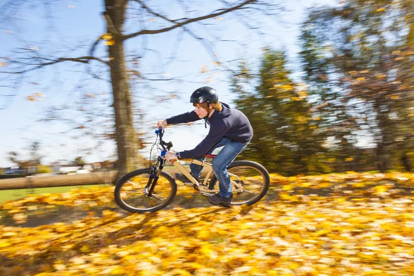 Chico salta monta su bicicleta con velocidad en zona abierta y disfruta de r —  Fotos de Stock