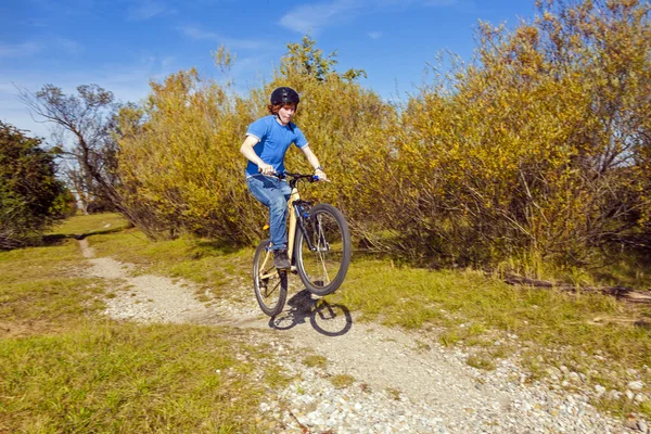 Menino pula com sua bicicleta de sujeira sobre rampas naturais — Fotografia de Stock