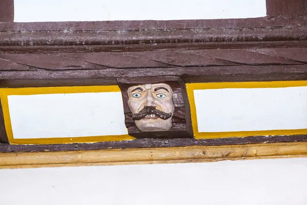 Hout snijwerk met grappige gezichten op hout balk van oude kader h — Stockfoto
