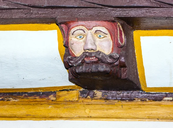 Резьба по дереву с забавными лицами на деревянной балке старой рамы h — стоковое фото