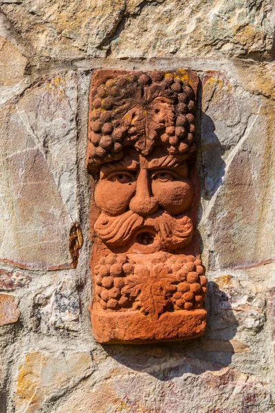 Viejo muro medieval de piedra con cara de bacco, el dios de la bodega — Foto de Stock