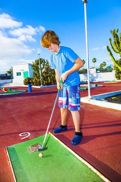 Boy playing mini golf in the course — Stock Photo, Image