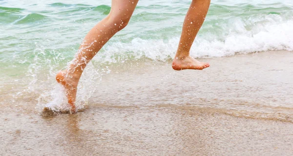 Fötter av pojke löper längs stranden — Stockfoto