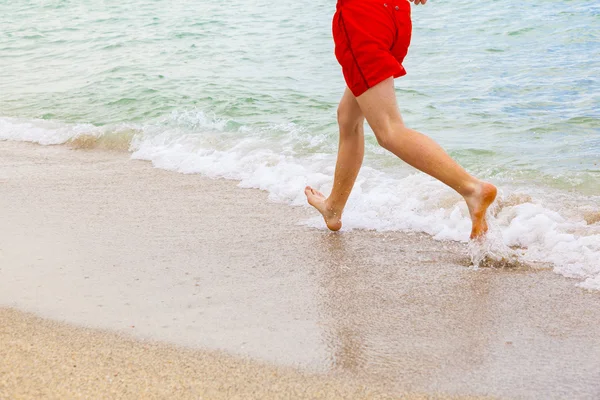 Fötter av pojke löper längs stranden — Stockfoto