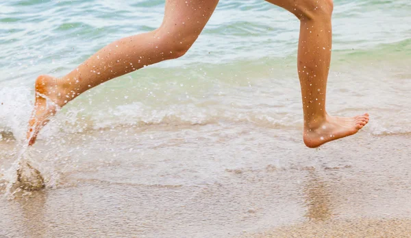 Fötter av pojke löper längs stranden — Stockfoto